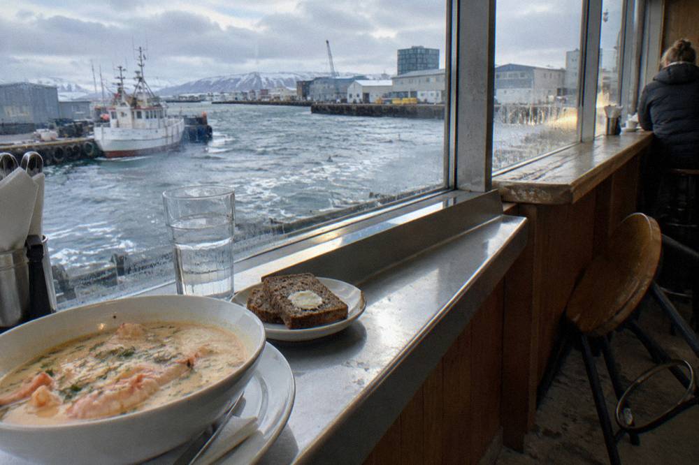 A food hall counter with plates of Icelandic seafood and bread being served