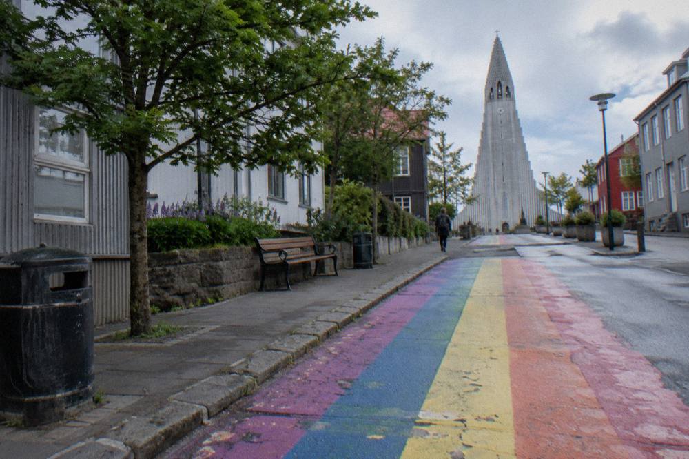Rainbow street painted on a pedestrian lane leading toward a tall church tower