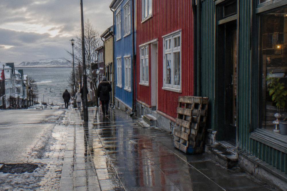 Rain-slicked Laugavegur street with shopfronts and low winter light