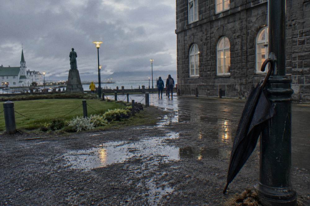 Wet pavement reflecting streetlights on a quiet Reykjavik corner at night