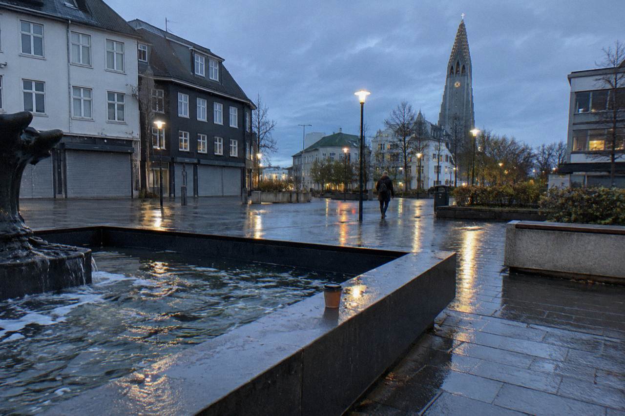 Illuminated street in downtown Reykjavik at dusk with closed shop fronts