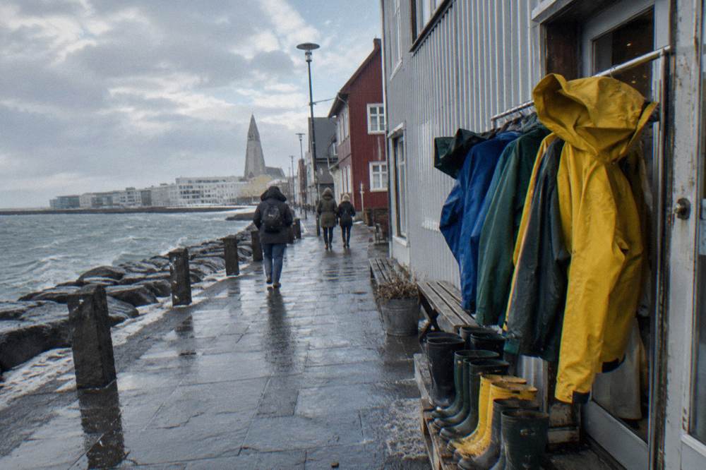 Rain jackets and boots on a rack beside a doorway on a Reykjavik street
