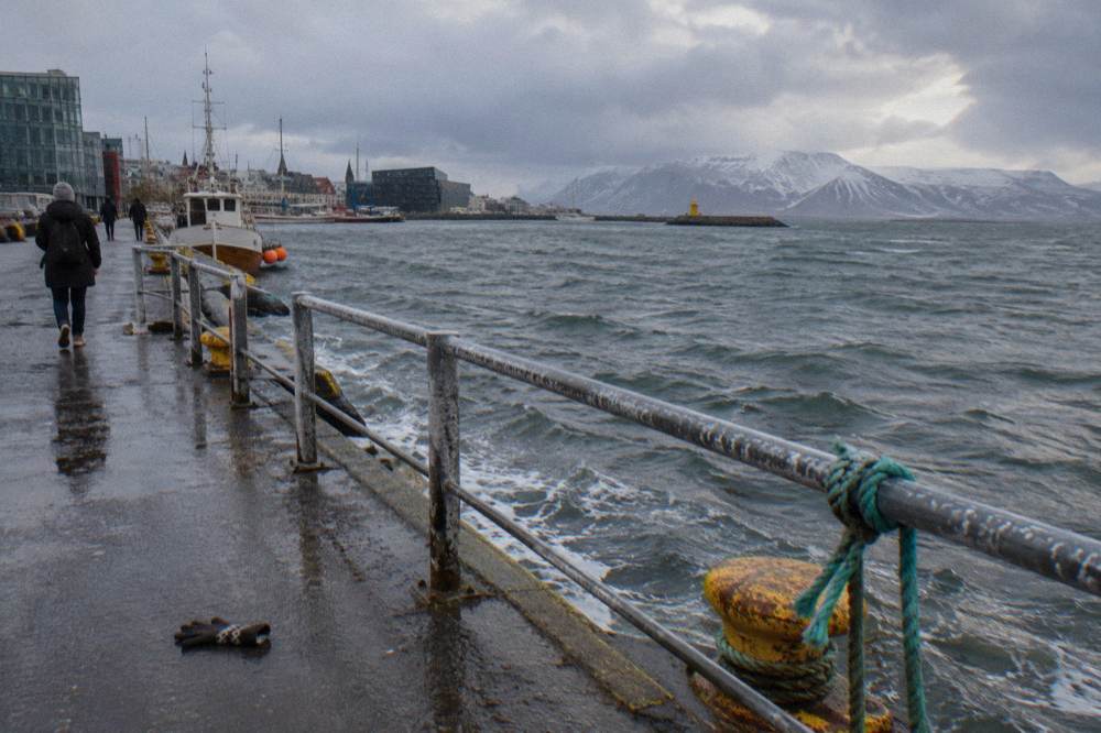 Wet harbour promenade in low winter light with rain clouds over the bay