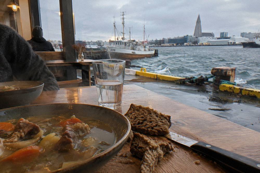 Food hall counter with dishes of lamb soup and fresh bread on wooden tables
