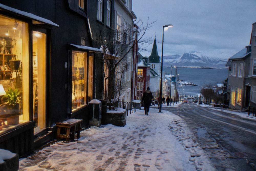 Snow dusted street in Reykjavik at dusk with warm light in shop windows