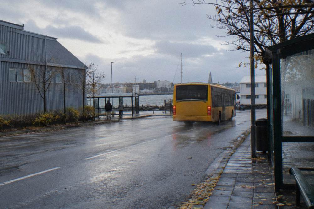 A city bus pulling away from a stop on a wide Reykjavik avenue