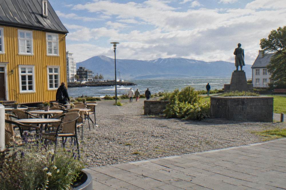 Shoppers walking along a bright downtown street with outdoor cafe seating in Reykjavik