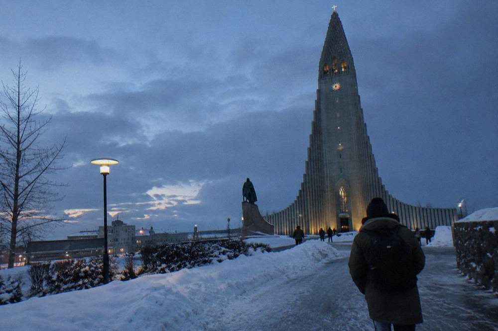 Hallgrímskirkja tower and statue at dusk with street lights along the approach in Reykjavik