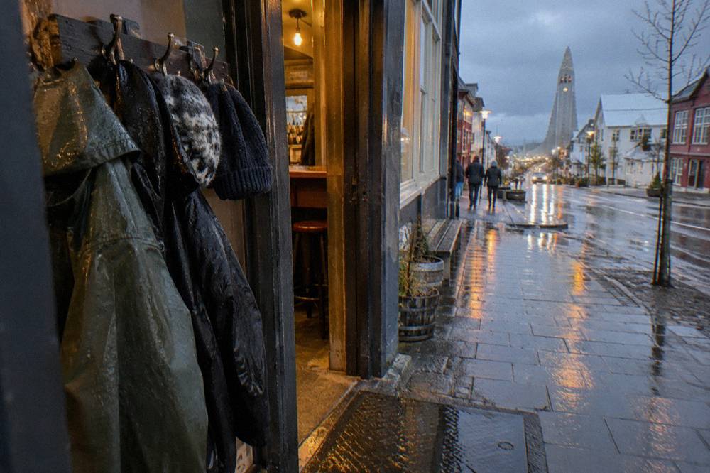 Rain jackets and wool hats hanging on hooks beside the entrance of a small city bar