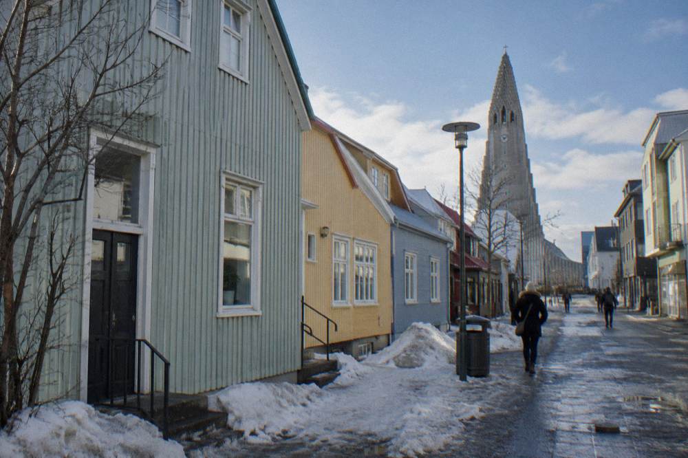 Pastel coloured townhouses along a quiet central street with the tower of the Hallgrimskirkja church rising behind them