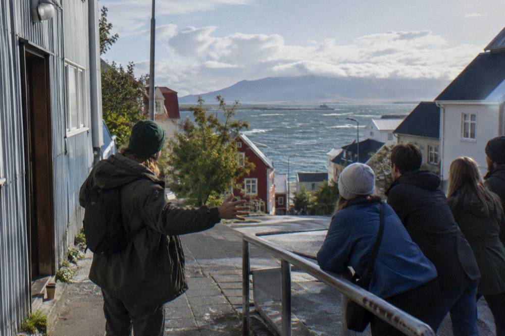 A storyteller gesturing to a cluster of listeners on a Reykjavik side street