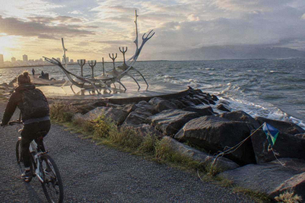 A cyclist riding a path along the Reykjavik seafront with mountains across the water