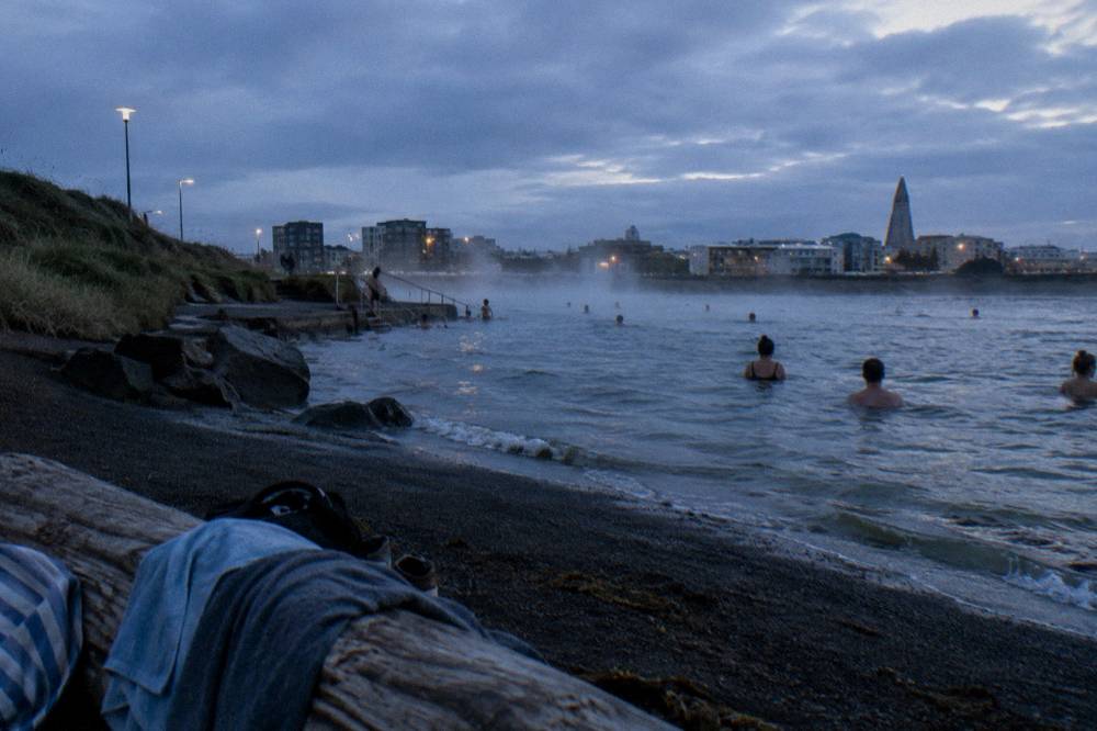 Steam rising from an outdoor geothermal pool in Reykjavik at dusk