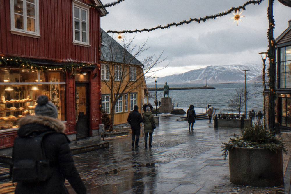 Pedestrians crossing a shopping street in central Reykjavik lined with colourful buildings