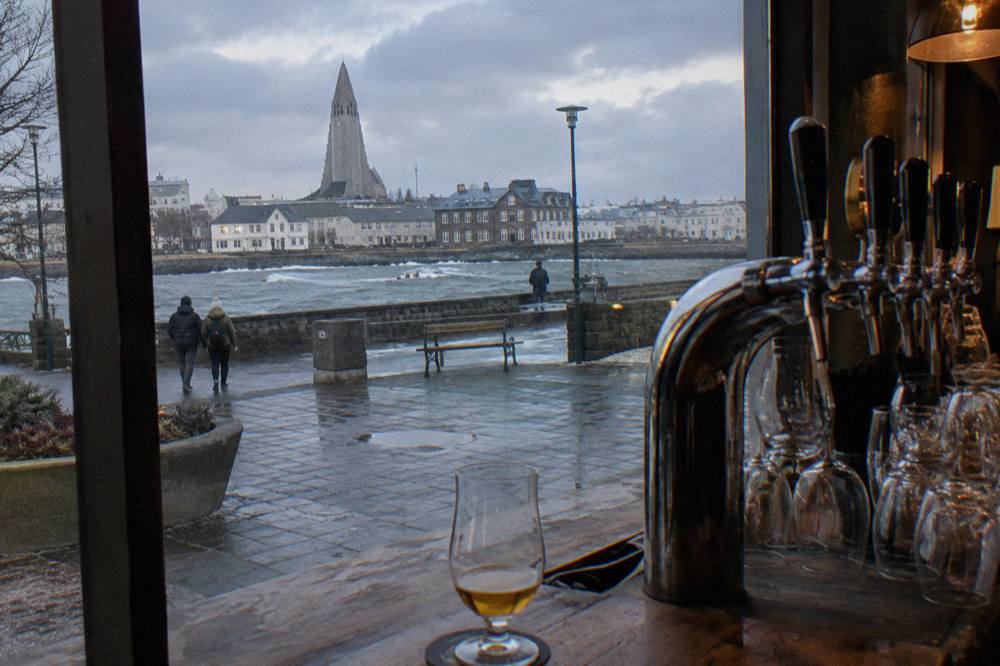 Craft beer taps and glasses arranged along a wooden bar counter in a Reykjavik pub