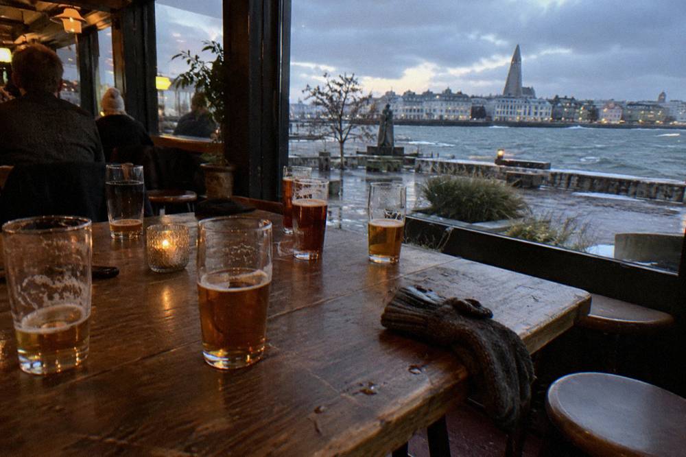 Group of beer glasses on a long wooden table inside a warmly lit Reykjavik bar