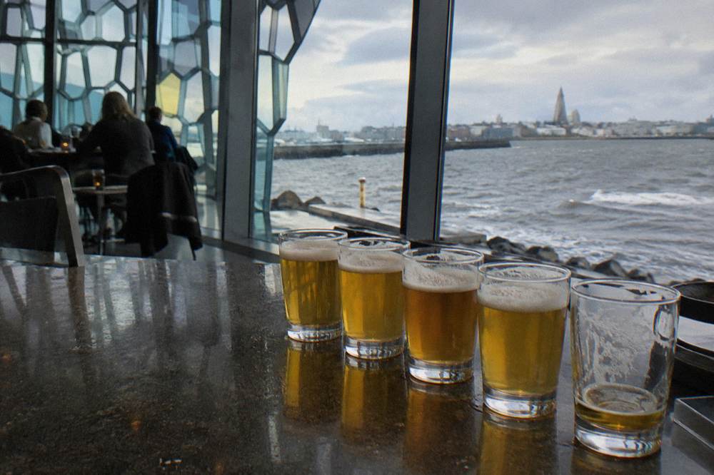 Close view of small tasting glasses of golden beer lined up on a dark bar top