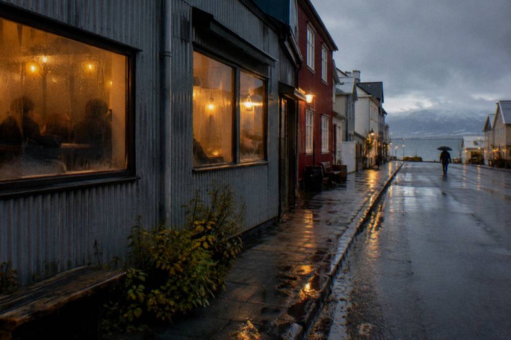 Evening street scene on a wet Reykjavik lane with warm light spilling from bar windows