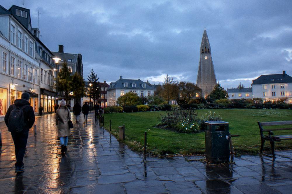 Walking street in central Reykjavik at dusk with shop lights reflecting on wet pavement