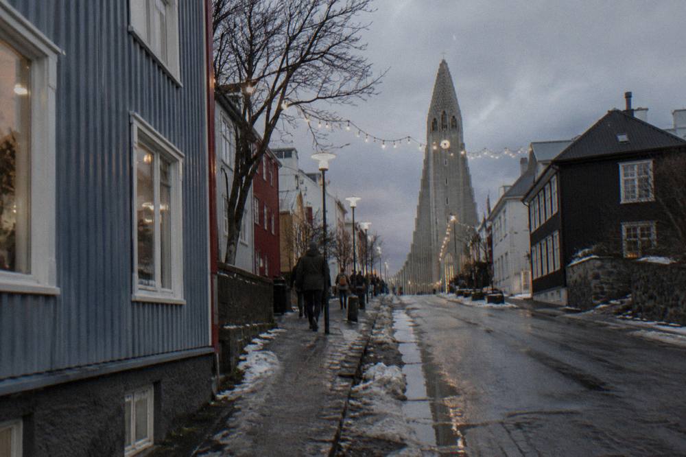 A decorated Christmas street in central Reykjavik with lights strung between buildings and snow on the pavement