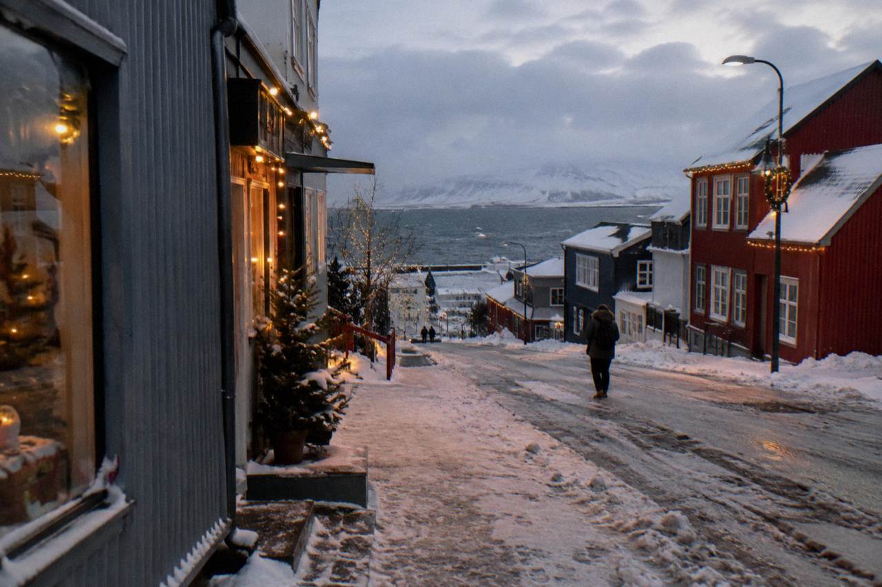 Festive lights glowing along a snowy Reykjavik street at dusk with Laugavegur shopfronts decorated for Christmas