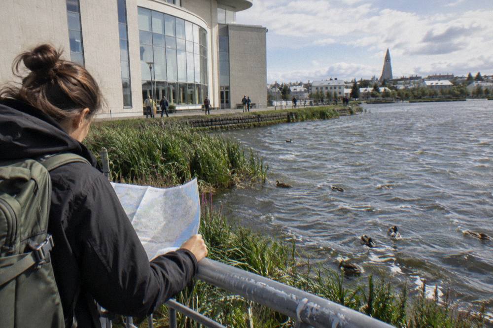 A visitor checking a paper map beside a museum entrance on a calm street in Reykjavik