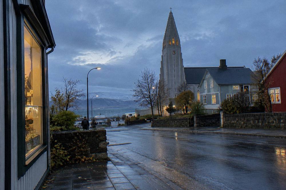 Reykjavik old town street at blue hour with lit windows and a church spire in the background