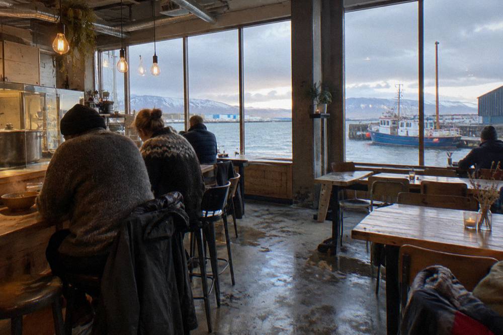 People gathered at a food hall counter under warm hanging lights in Reykjavik