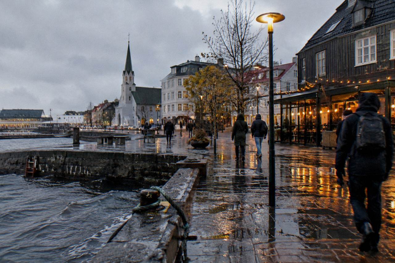 Illuminated street in central Reykjavik at dusk with warm lights reflecting on wet pavement