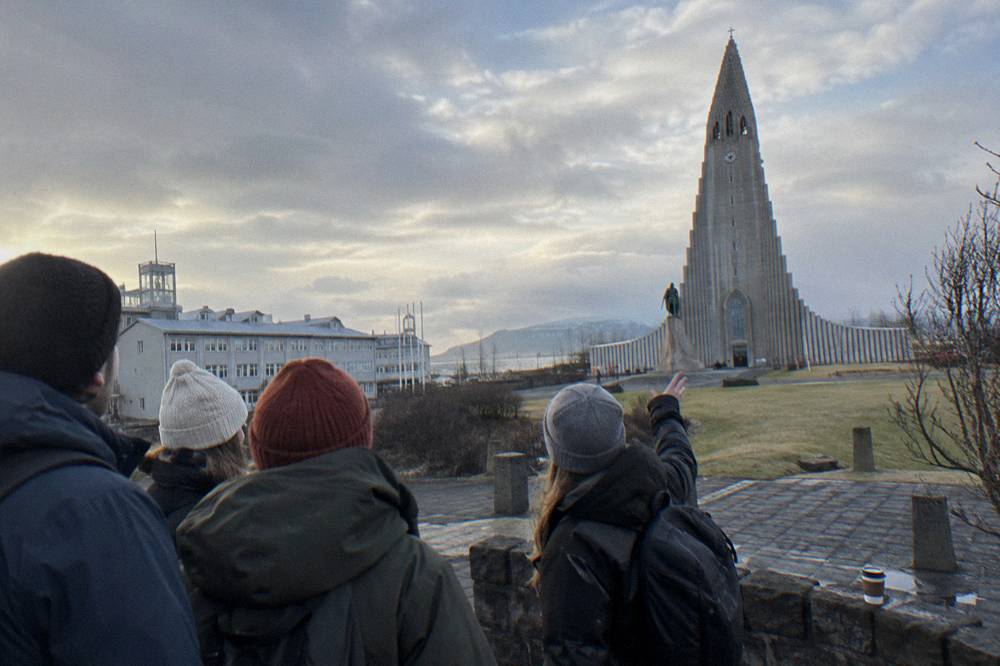 A guide gesturing to a small group gathered on a downtown Reykjavik street corner