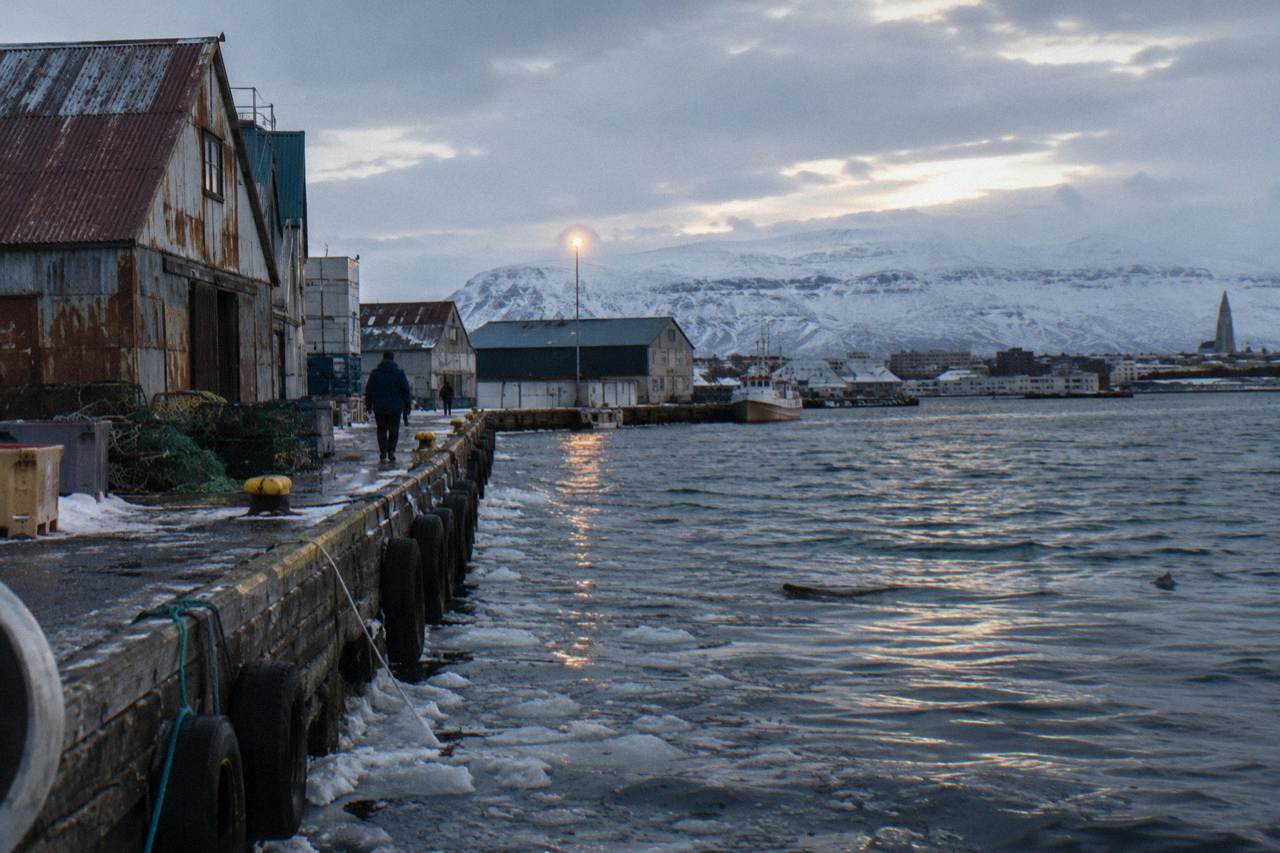 Old harbour buildings and snow-dusted mountains beyond the Reykjavik waterfront at dusk
