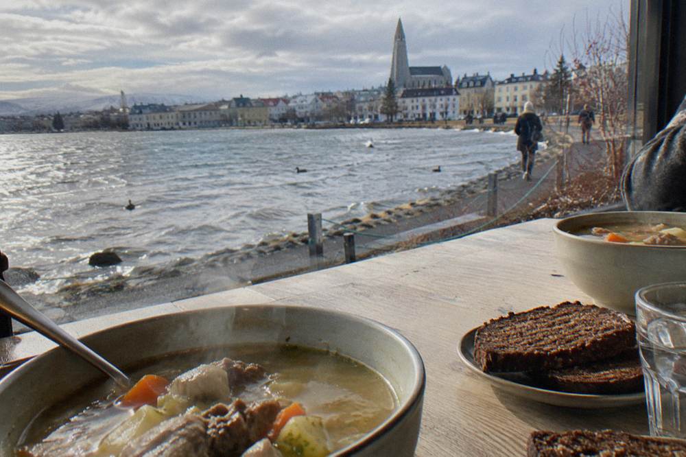 Bowls of lamb soup and rye bread on a wooden restaurant table
