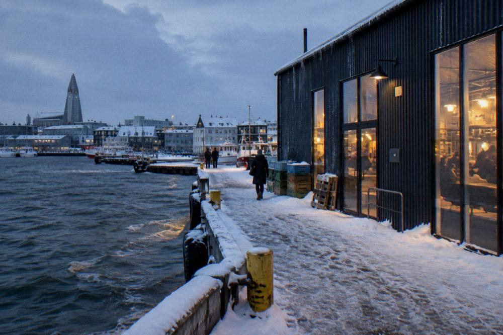 Harbour district food hall lit up at dusk with snow on the ground