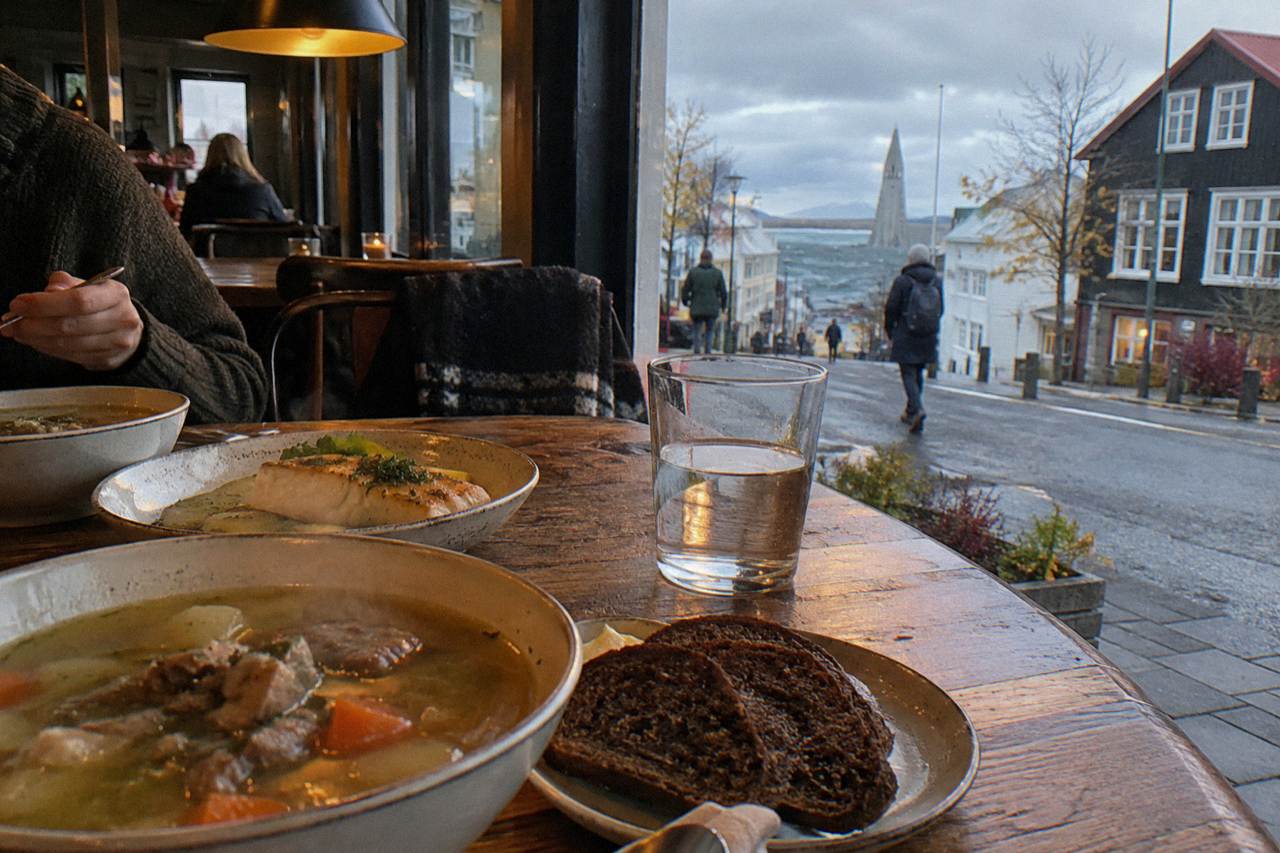 Long wooden table in an Icelandic restaurant with plates of lamb soup, rye bread and seafood