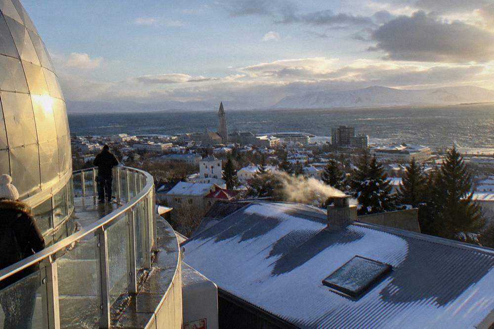 Low golden sunlight over Reykjavik rooftops seen from a high vantage point in late afternoon