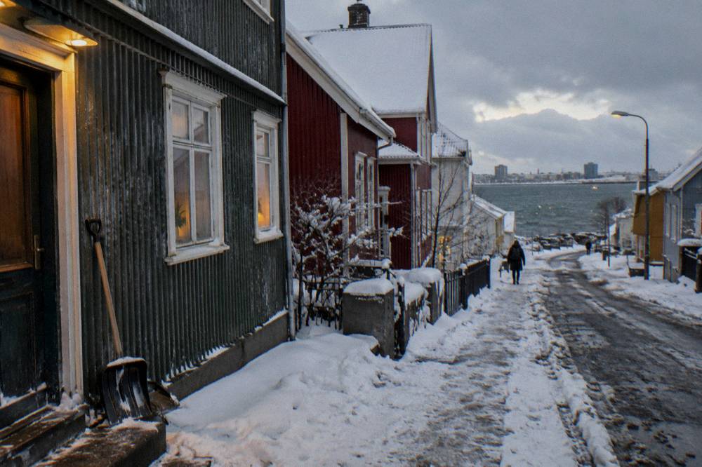 Fresh snow on Reykjavik rooftops with warm window light in the late afternoon