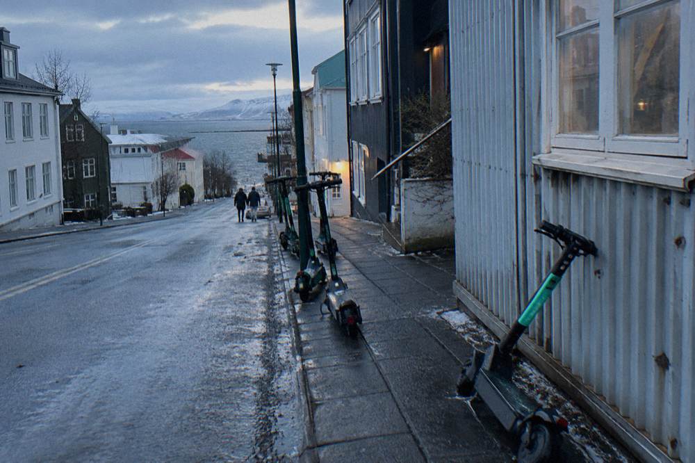 A row of parked electric scooters beside a pavement in the city centre