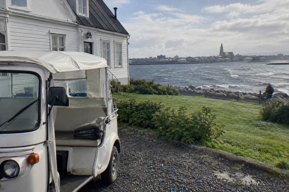 A small motorised tuk tuk vehicle parked on a street corner in Reykjavik