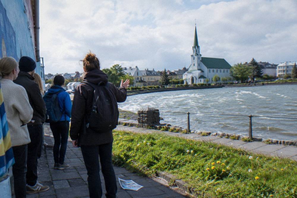 Tour group listening to a guide beside a painted wall in downtown Reykjavik