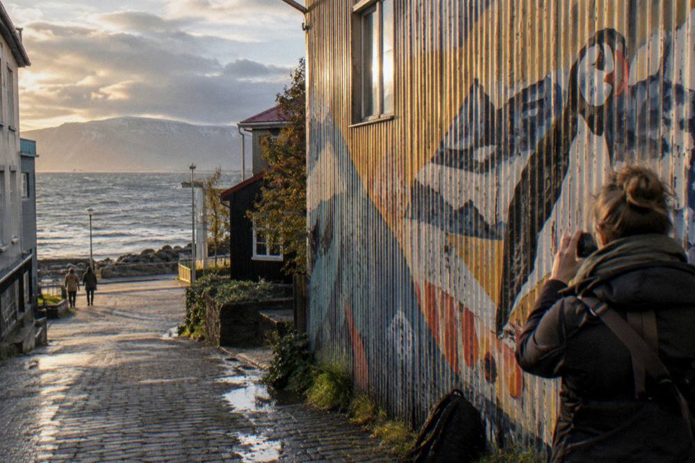Visitor photographing a large painted wall in a Reykjavik side lane