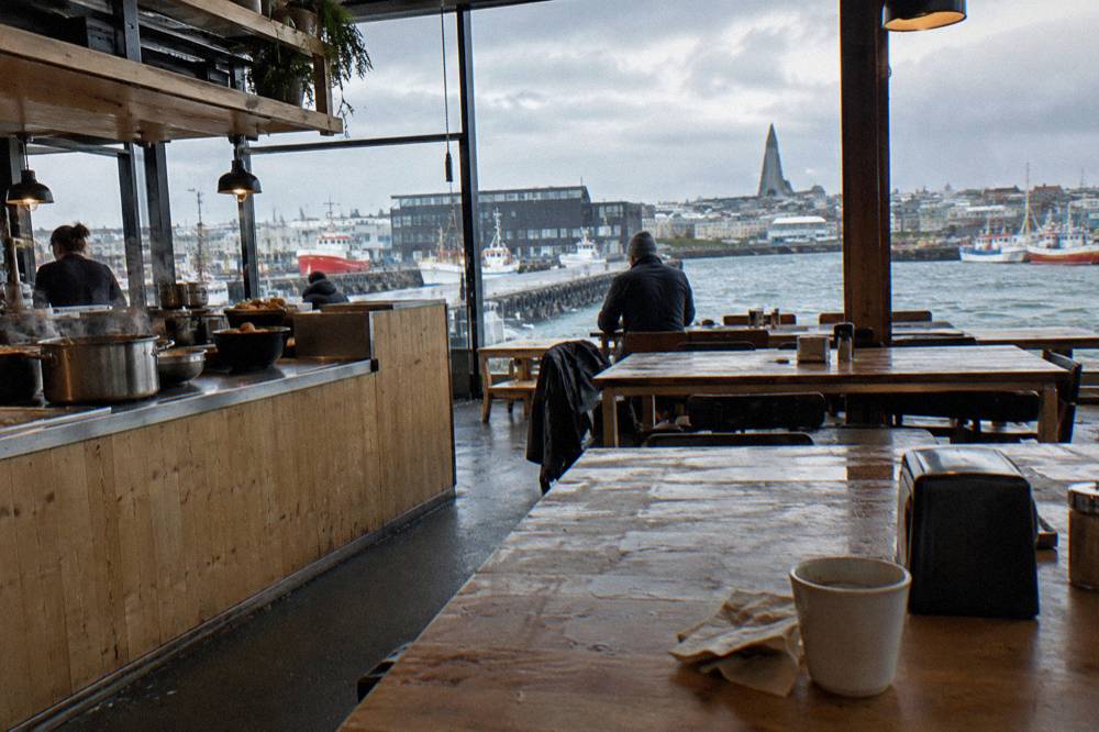 Interior of a bright Icelandic food hall with counters of food and shared tables under warm lights