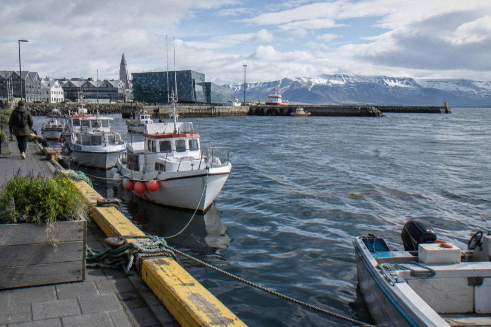 Waterfront path along Reykjavik old harbour with moored boats and mountains across the bay