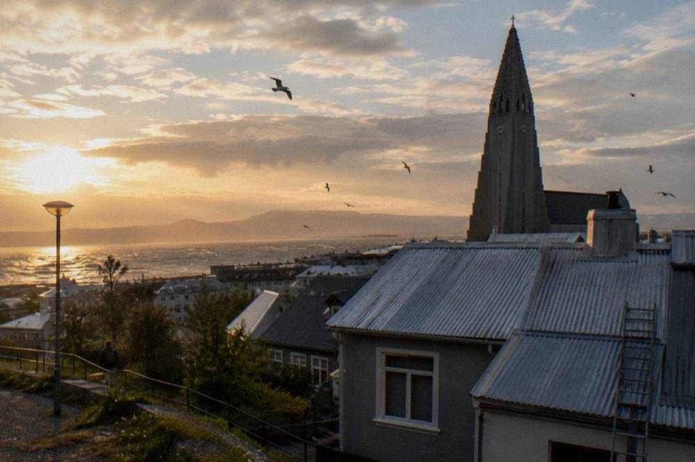 Golden evening light over Reykjavik rooftops with the Hallgrímskirkja tower silhouetted against the sky