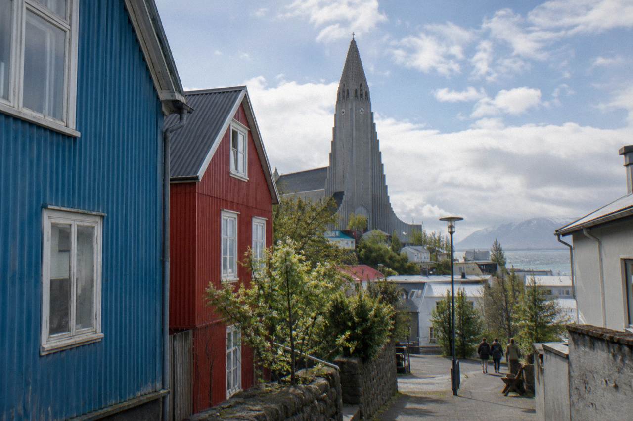 Colourful corrugated iron houses on a quiet Reykjavik street with the Hallgrímskirkja church tower behind them