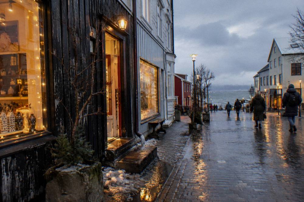 Wet cobblestone street in Reykjavik reflecting shop lights on a dark winter afternoon