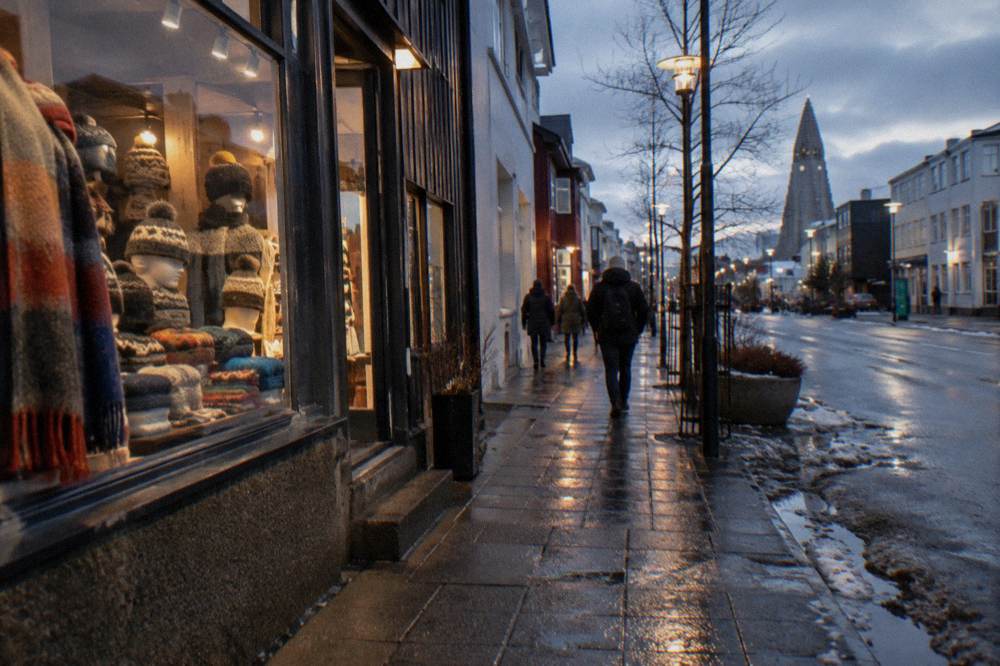 Parked bicycles and a wool shop front on a wet Reykjavik street reflecting streetlights
