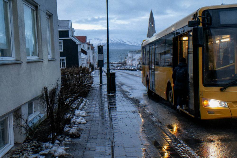 A city bus parked at a stop beside a low building in central Reykjavik