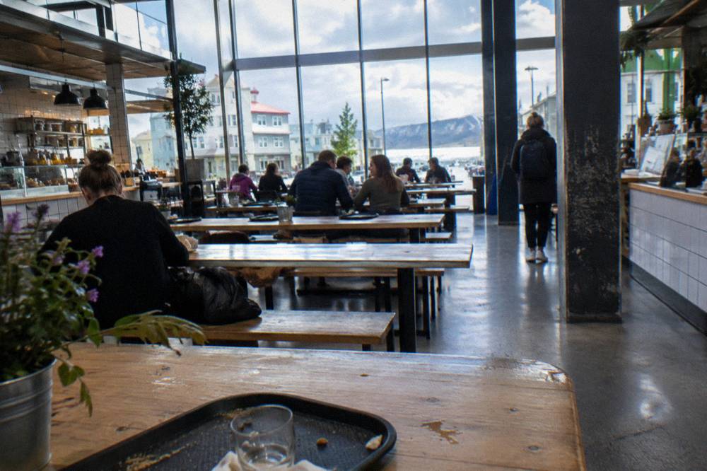 A bright food hall with communal wooden tables and vendor stalls
