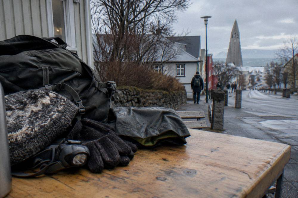 A packed daypack with hat, gloves, headlamp and rain shell on a table