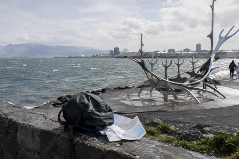 A compact daypack on a bench overlooking the Reykjavik waterfront in overcast light